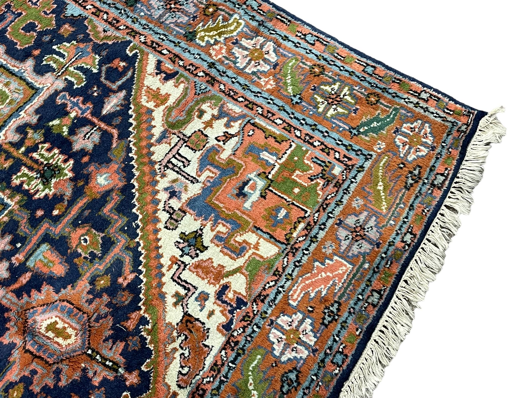Persian Heriz indigo and rust ground rug, central geometric star medallion decorated with stylised foliate motifs, the border decorated with stylised flower heads