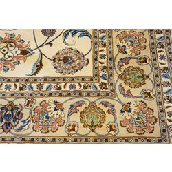 North East Persian Mashad hand-knotted carpet, ivory field decorated with an all-over scrolling floral vine design incorporating stylized palmettes, deer, rosettes and floral sprays enclosed by a conforming floral vine border between multiple guard stripes, cotton fringe ends