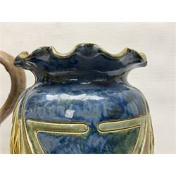 Early 20th century Royal Doulton stoneware vase, decorated with a stylized floral design below a wavy rim, monogrammed B.N, possibly for Bessie Newbery, H28cm, together with an early 20th century glazed jug, heavily carved throughout (2)