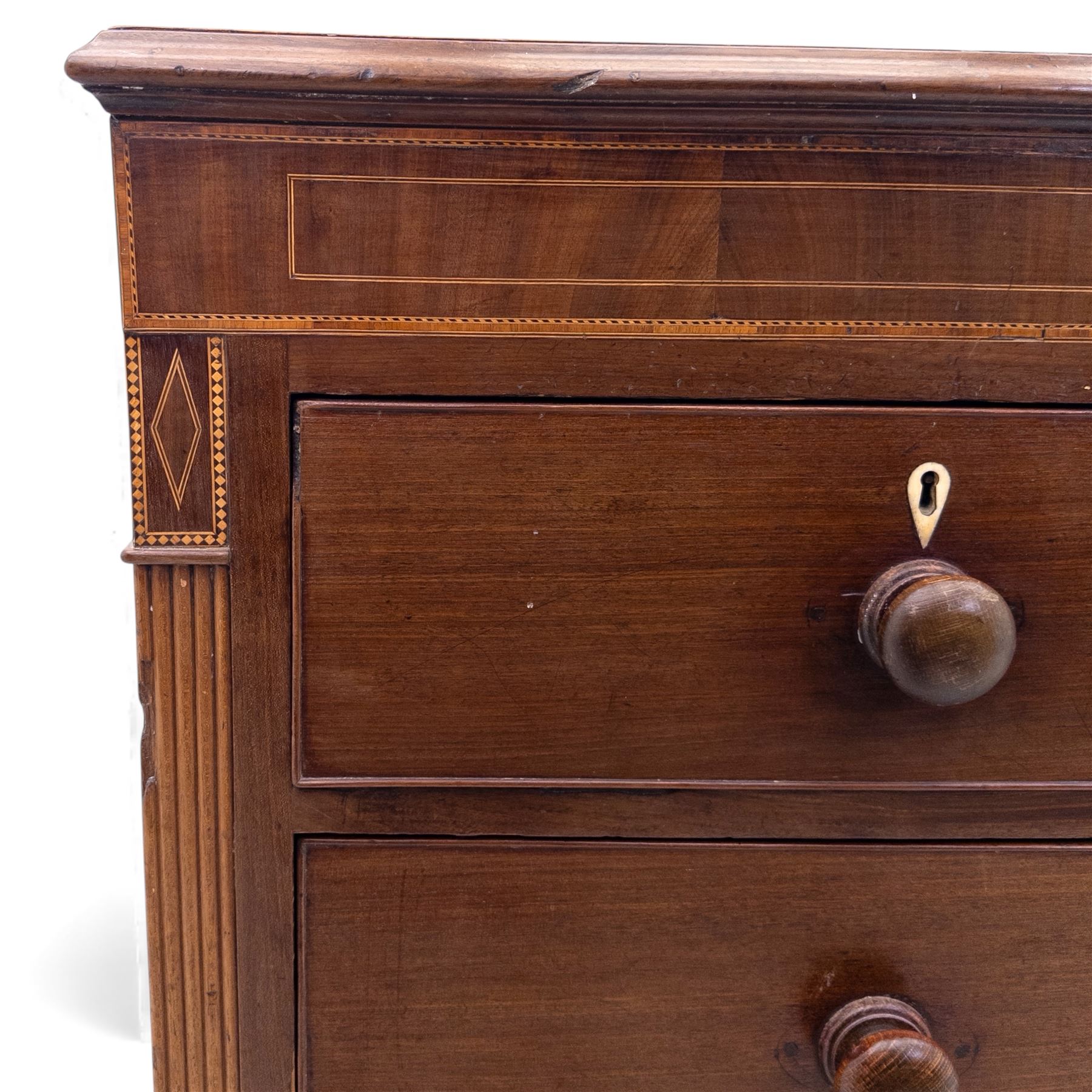 Early 19th century mahogany chest of drawers, the rectangular top with boxwood line inlay above two short and three long graduating drawers, each with turned wooden knobs and bone escutcheons, flanked by fluted uprights with diamond inlaid panels, on shaped bracket feet