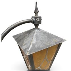 REVO Electric Co. Ltd., Tipton - early 20th century cast iron street lamp standard, the later hexagonal lantern with amber leaded glazing and pointed finial, supported on a swan-neck bracket above a ring-turned capital, tapering column and ladder rest, terminating in a moulded scrolling foliate-decorated base with lappet collar, stamped REVO

Provenance: formerly installed as street lighting in Prestwich, Greater Manchester