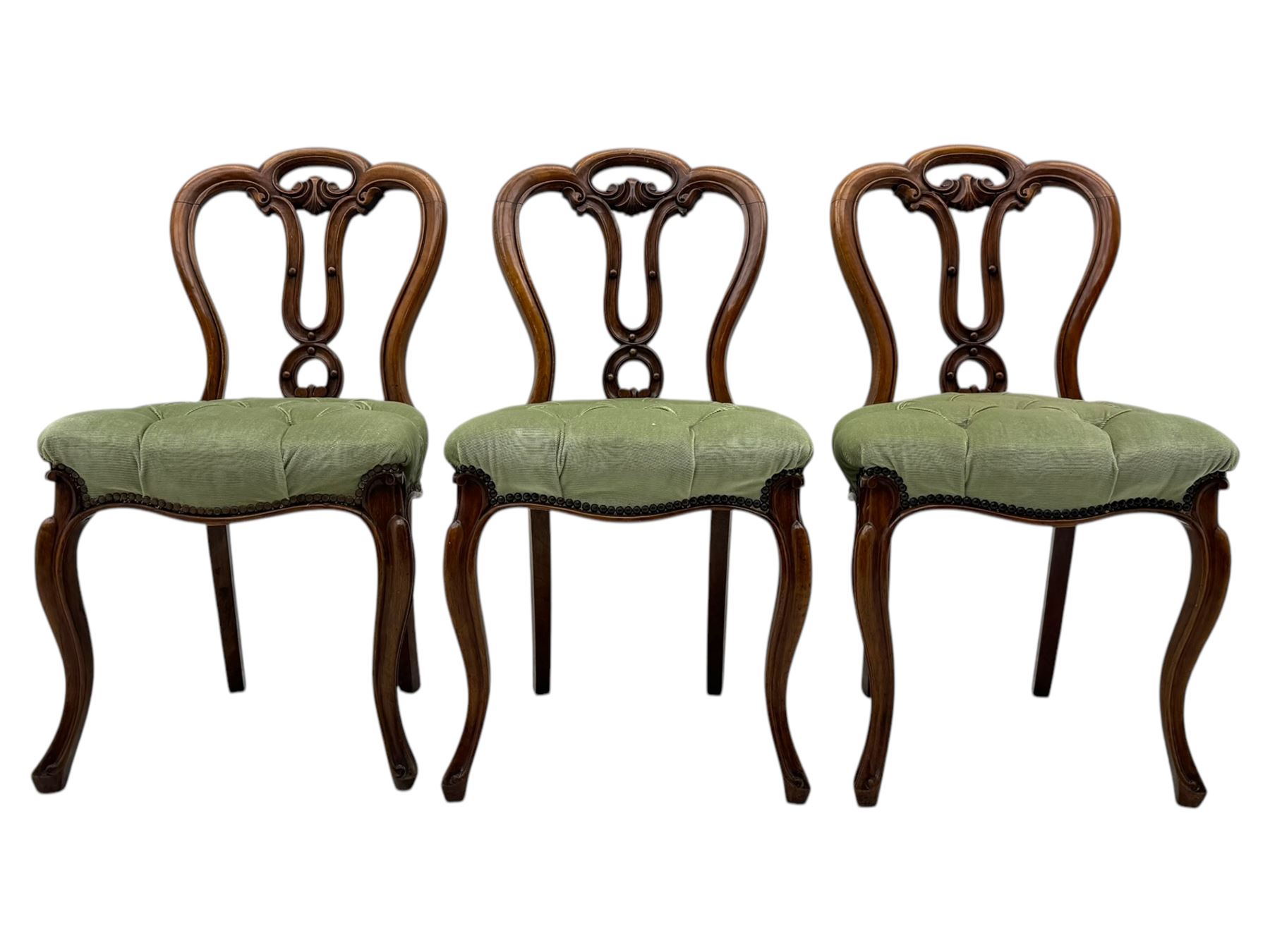 Set of six carved Victorian walnut balloon back dining chairs, button upholstered in green velvet fabric, back with foliate carved decoration supported on scroll form legs 