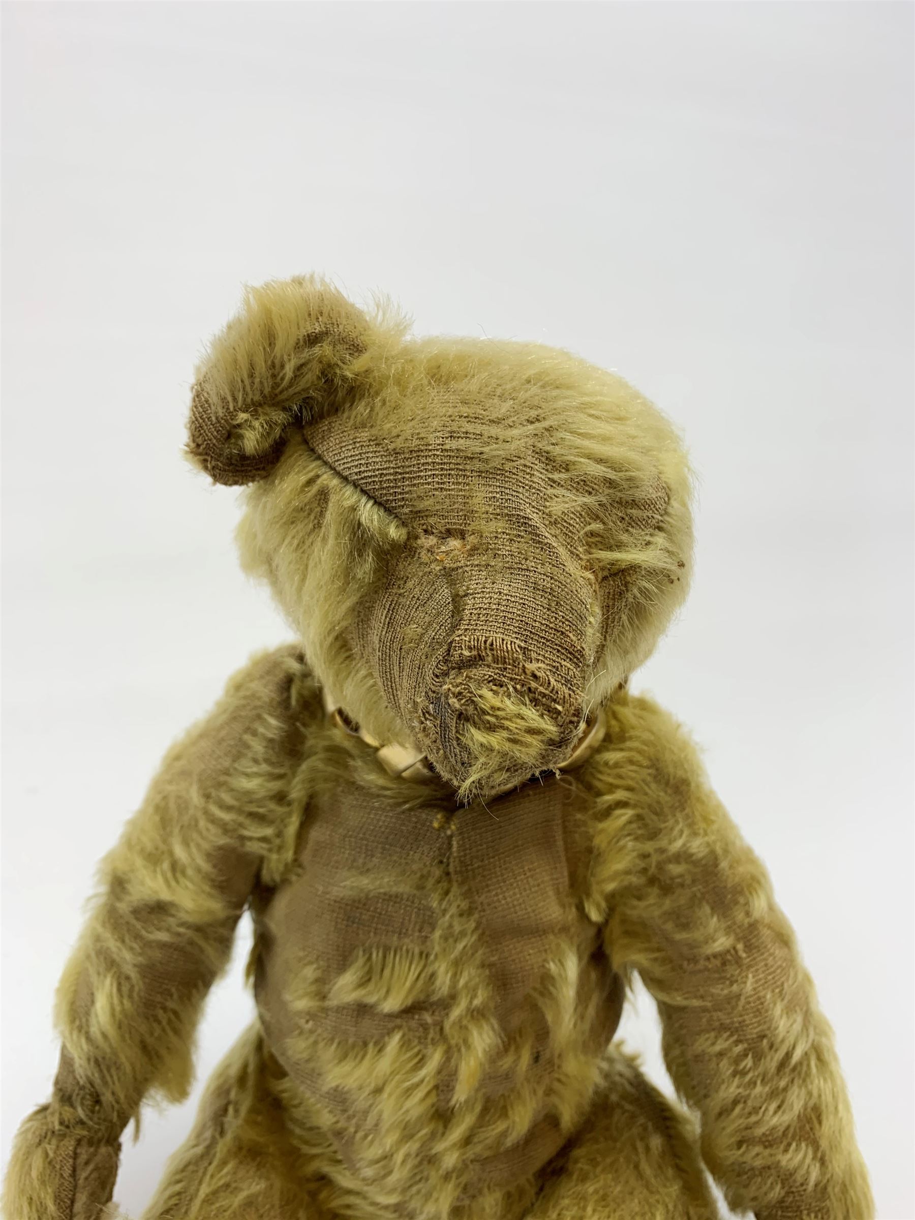Early 20th century English teddy bear, with wood wool filled body with jointed limbs, felt covered paw pads, five claw stitching to feet and elongated arms with spoon shaped paws H14