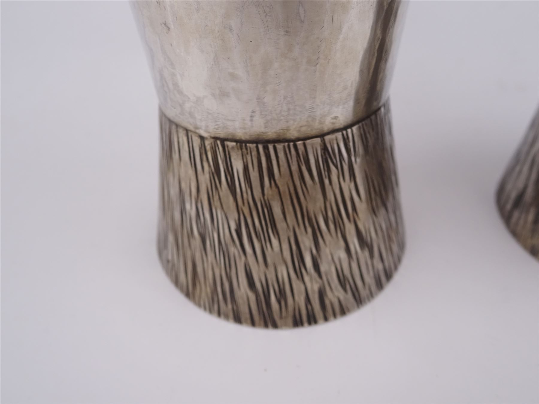 Pair of modern Guild of Hull Silversmiths silver goblets, the bowls each of tapering cylindrical form, with spot hammered finish, upon a tapering foot, etched with abstract lines, hallmarked J & KR, Birmingham 1983, also marked with the three crowns mark of the Guild of Hull Silversmiths, H11.6cm
Notes: Abraham Barachin was the last Hull silversmith to use the Hull mark of three ducal coronets in around 1706. However in 1983 the Assay Offices of Great Britain and the City of Kingston upon Hull granted the Guild of Hull Silversmiths permission to use the City's Coat of Arms as an additional mark on pieces they produced