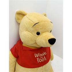 Very large plush covered figure of Winnie The Pooh in a seated position with black plastic eyes, black felt nose and eyebrows, red open mouth and T-shirt with name to front H42