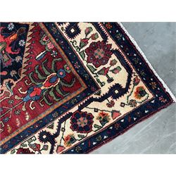 Persian Hamadan rug, the red ground field decorated with two floral medallions and stylised flower heads, repeating guarded border