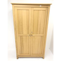Light oak double wardrobe, projecting cornice, two doors enclosing fitted interior, stile supports 