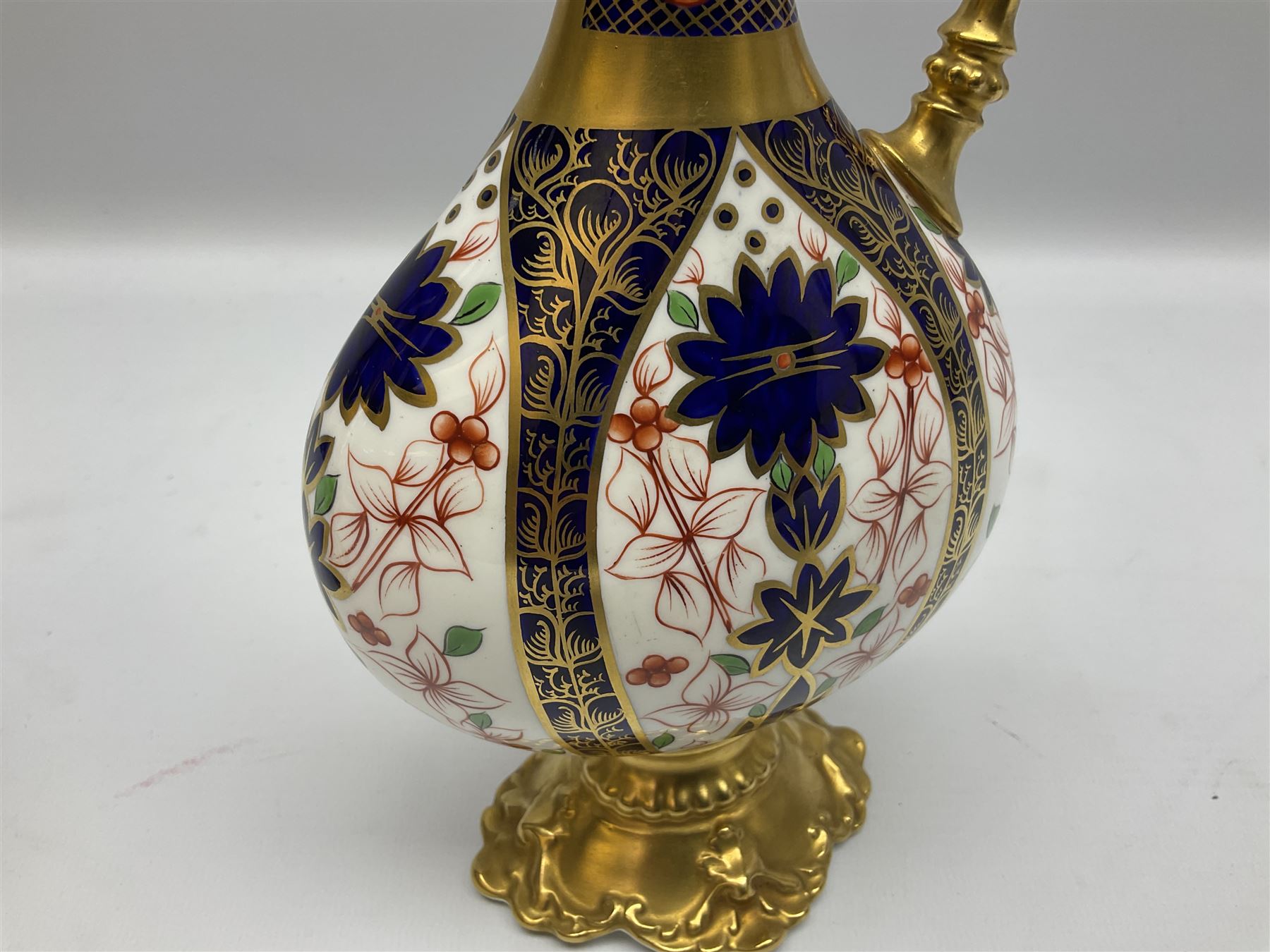 Pair of mid 20th century Royal Crown Derby Imari 1128 pattern Kedleston ewers, each with gilt scroll handle and neck, upon a gilt quatrefoil foot, each with printed marks beneath, H25.5cm