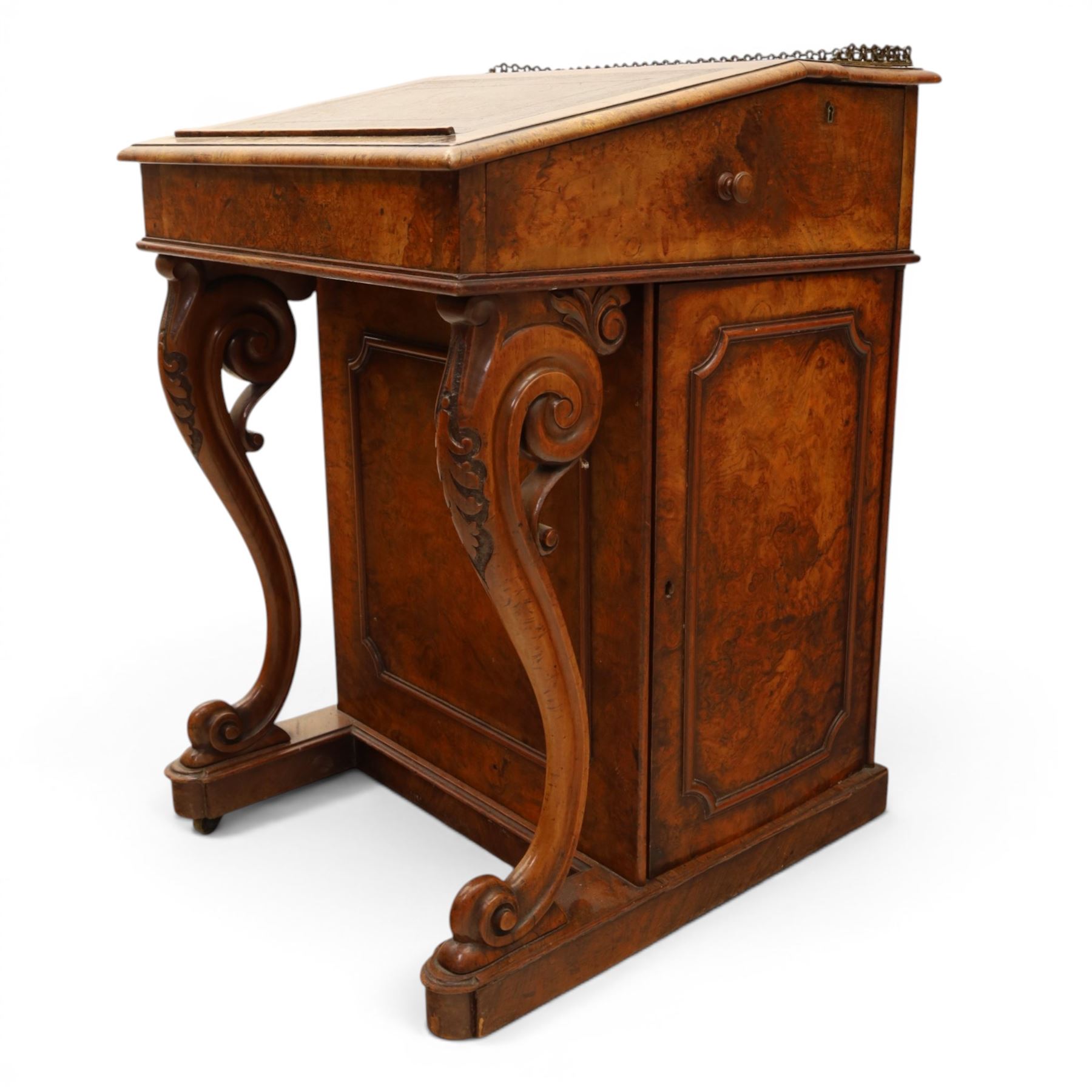 Victorian figured walnut Davenport, the fixed fall with drawer to the side enclosing writing compartment, green tooled leather writing inset, galleried back rail, right side fitted with four drawers behind a panel, opposing panelled side, raised on carved cabriole front supports with scroll terminals and platform base