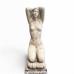 20th century composite stone garden figure, modelled as a kneeling nude female with arms raised behind her head, mounted on an integral cushion, the squared ogee pedestal moulded with acanthus leaves and flower heads, in a white painted and weathered finish