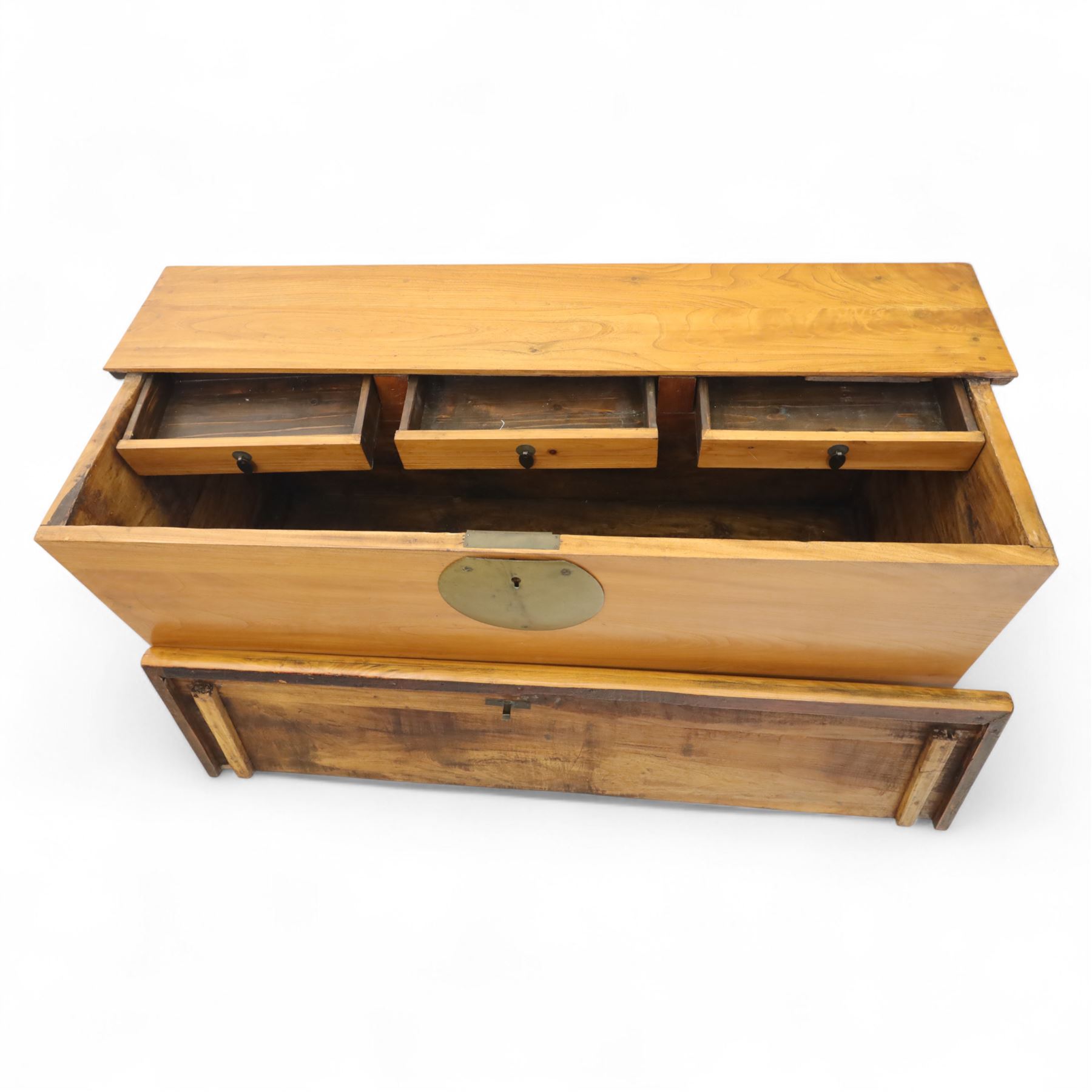 Burmese hardwood and brass inlaid marriage chest, the hinged top enclosing a fitted interior with small drawers, the front decorated with a circular brass medallion, raised on a plinth base