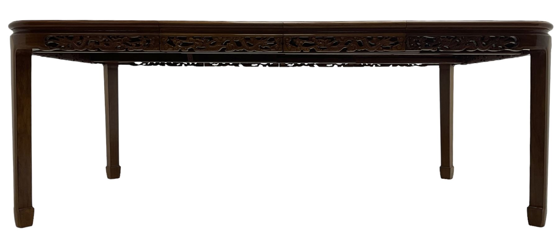 Late 20th century Chinese carved hardwood extending dining table, rectangular panelled top with rounded corners over a pierced frieze carved with dragon motifs and scrolling foliate decoration, with two additional leaves