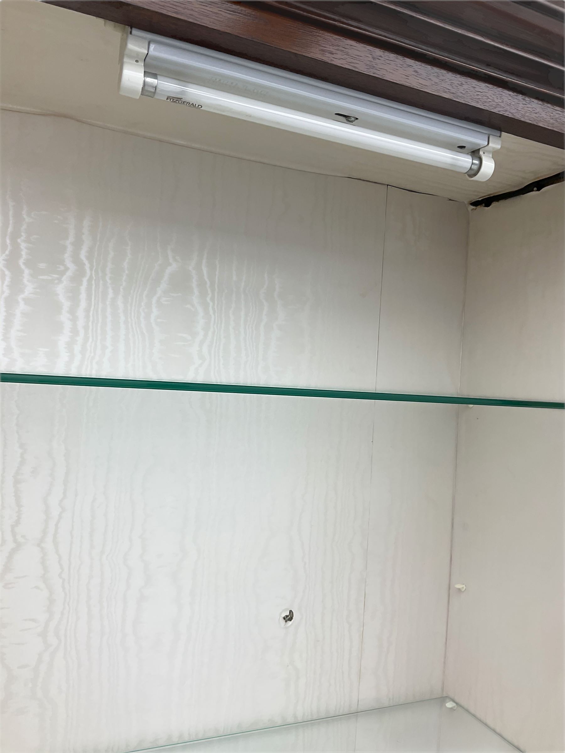 Mahogany display cabinet with hidden compartment, projecting cornice over single glazed door enclosing glass shelves, double panelled cupboard below, the interior with button releasing sliding back compartment, on bracket feet