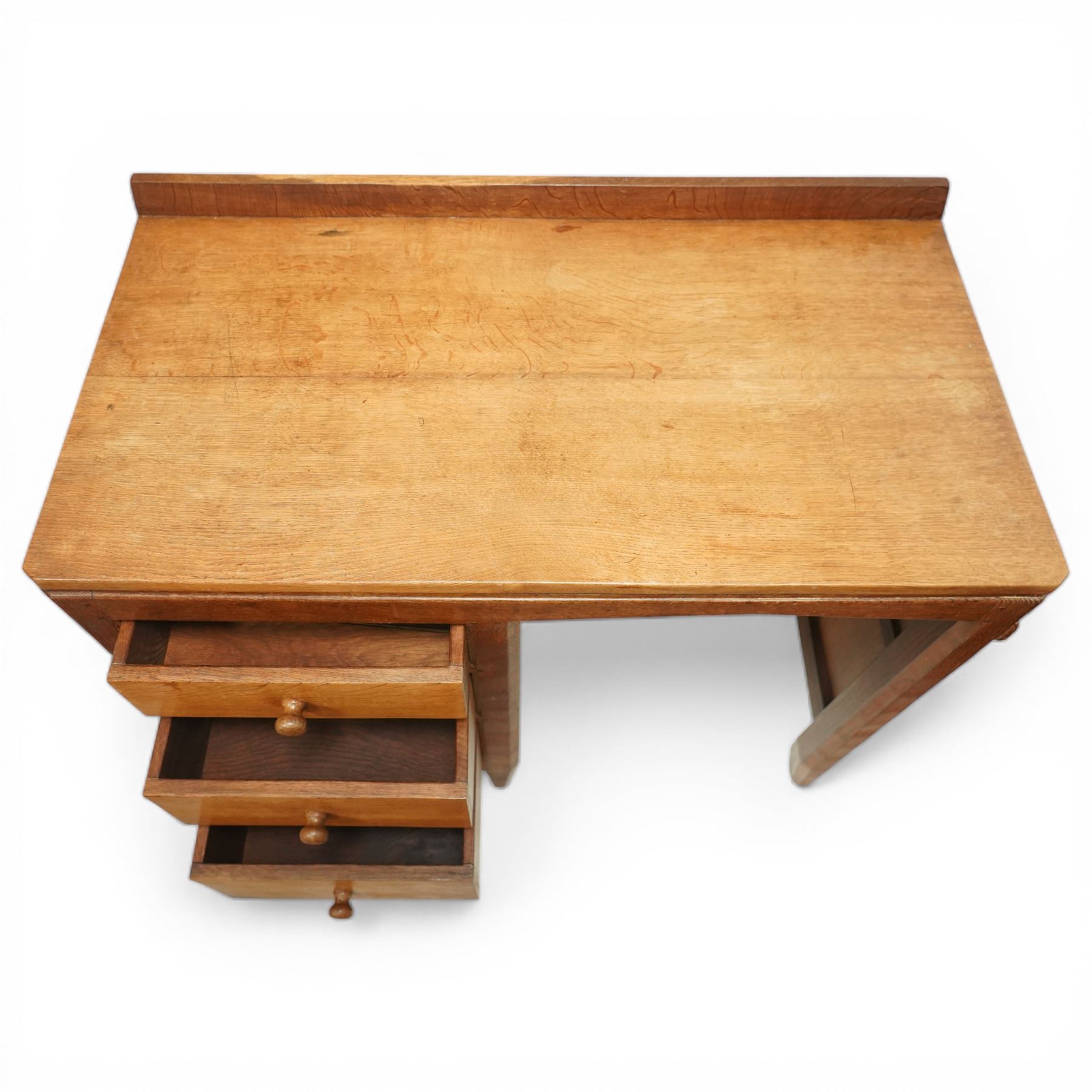 Rabbitman - oak single pedestal desk, adzed top with galleried back, with three graduating drawers with turned wooden knobs, enclosed kneehole with adzed detailing throughout the panelling and supports, with carved rabbit signature, by Peter Heap of Wetwang