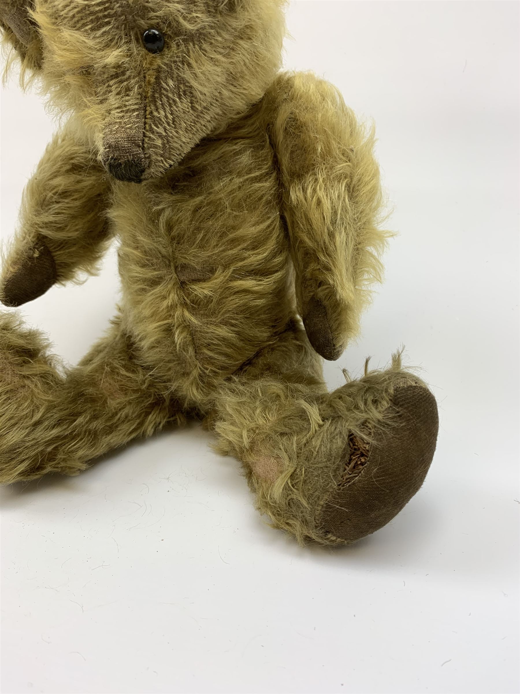Early 20th century English teddy bear, WW1 period, with wood wool filled mohair body, fixed head with one boot button eye and vertically stitched nose and mouth and jointed limbs with cloth paw pads H16