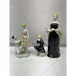 Mid-century Polonne figure group depicting a young girl at a dress fitting, with printed blue mark beneath, together with another USSR figure of a seated young girl in black dress, stamped beneath, and further figure of a lady in black dress and shawl, with impressed 435 and printed marks beneath, H28cm