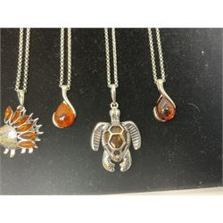 Fifteen silver Baltic amber pendant necklaces, including hedgehog, kingfisher, bee, turtle and dinosaur designs, all stamped 925, on black velvet necklace display stand