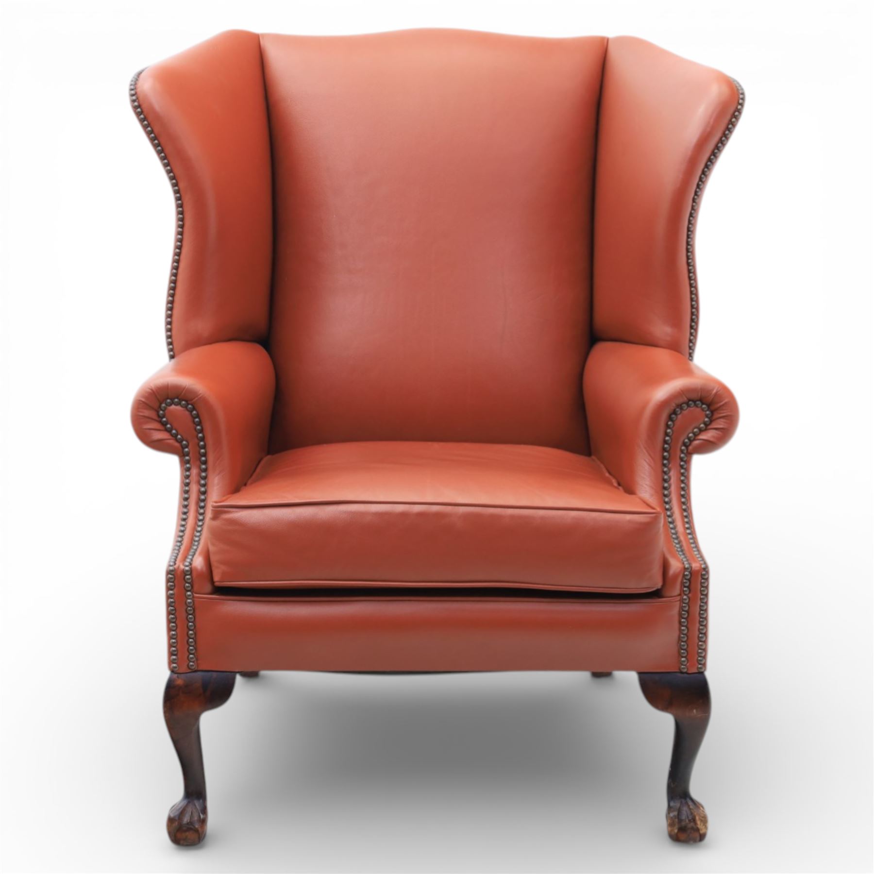 Georgian design red leather wingback armchair, with shaped back and scrolled arms, and close brass studded trim, upon cabriole front legs with claw and ball feet