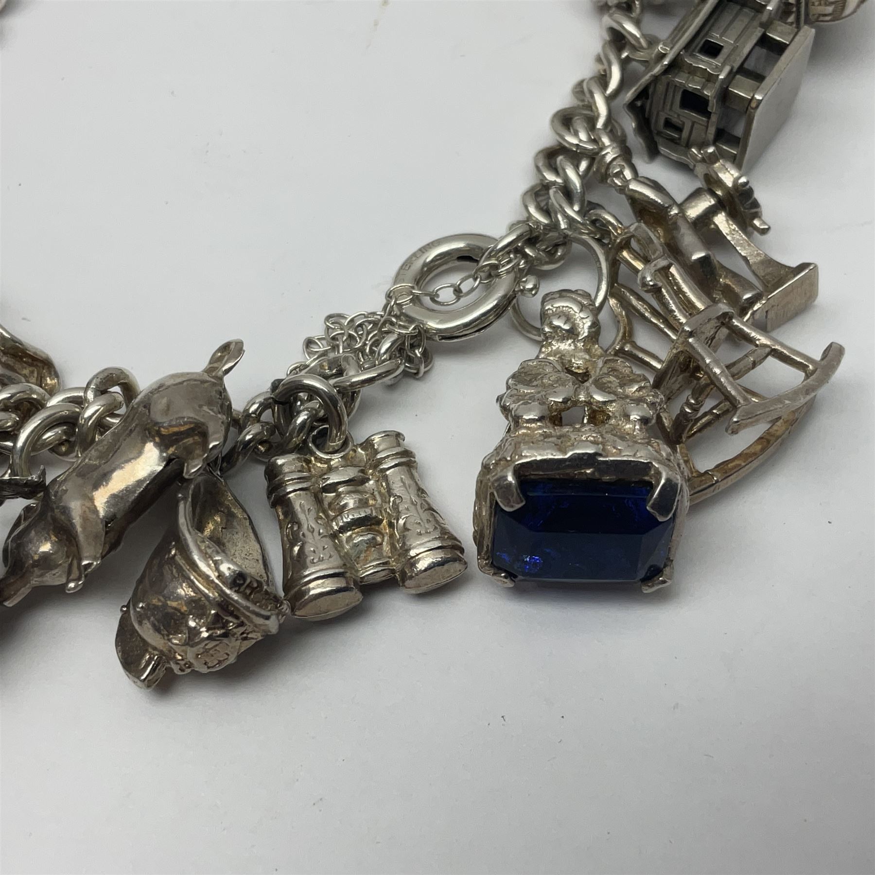 Silver charm bracelet, with twenty eight charms, including typewriter, rocking chair, carriage, cauldron, etc