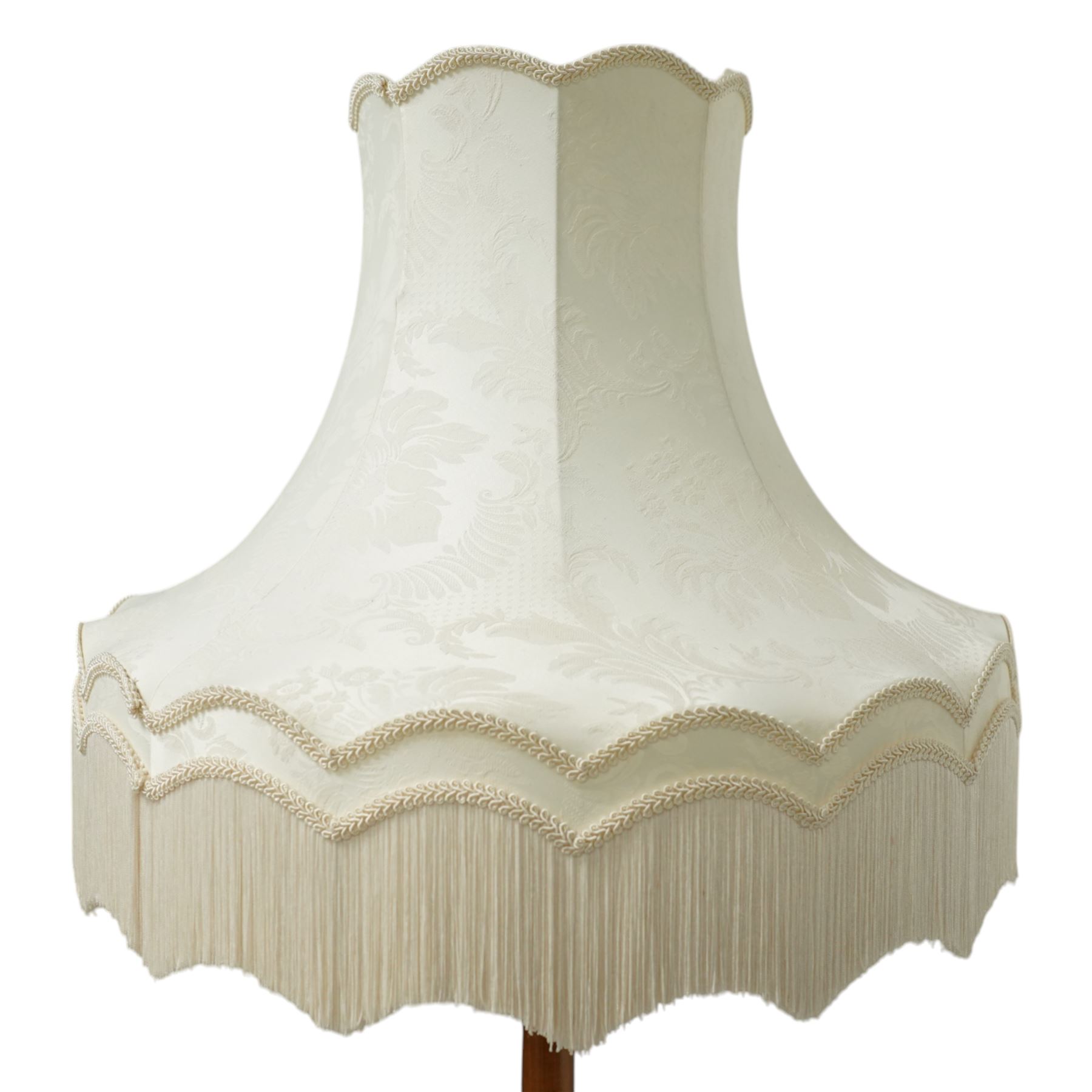 20th century walnut standard lamp, flared and faceted column over circular stepped base with shaped feet, with later scalloped cream fabric shade and fringe trim