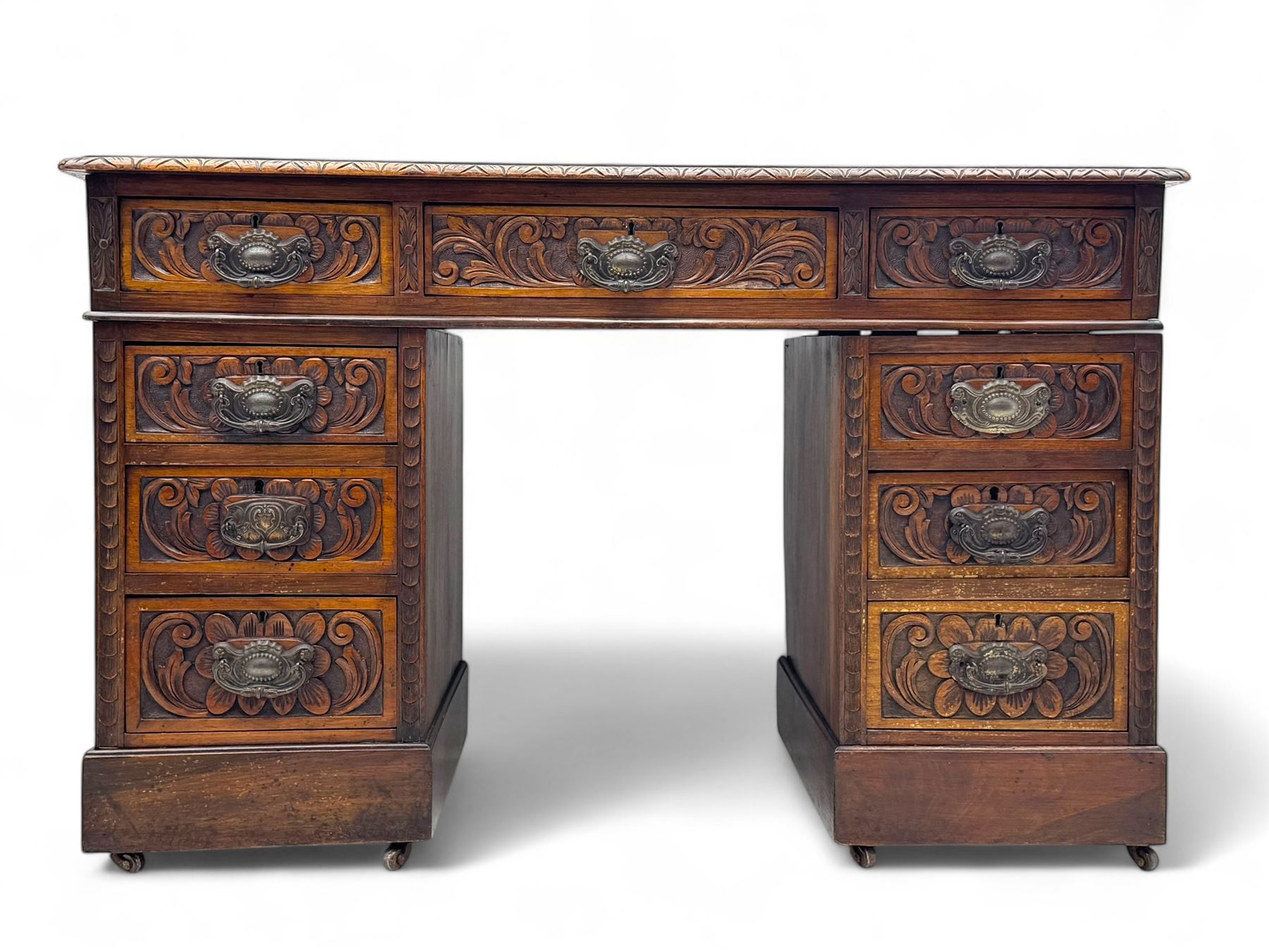 Late 19th century carved oak twin pedestal desk, rectangular top with inset leather writing surface, fitted with nine drawers, carved with scrolling foliate decoration, in three sections