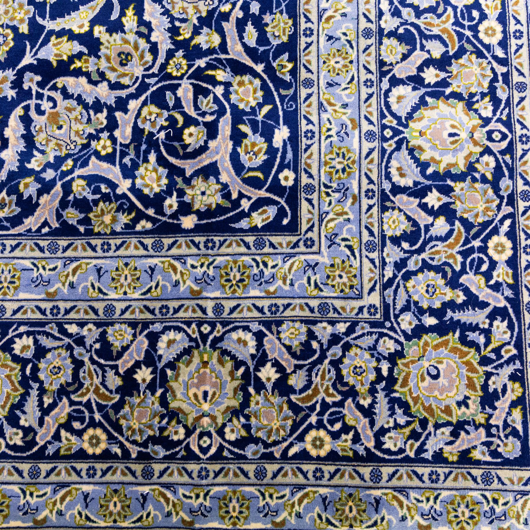 Central Persian Kashan hand-knotted carpet, deep indigo blue field densely decorated with all-over vine, palmette and flowering sprays arranged in a symmetrical pattern enclosed by broad navy border of stylized palmettes, and foliate vine decoration between multiple guard stripes, with cotton fringe ends 