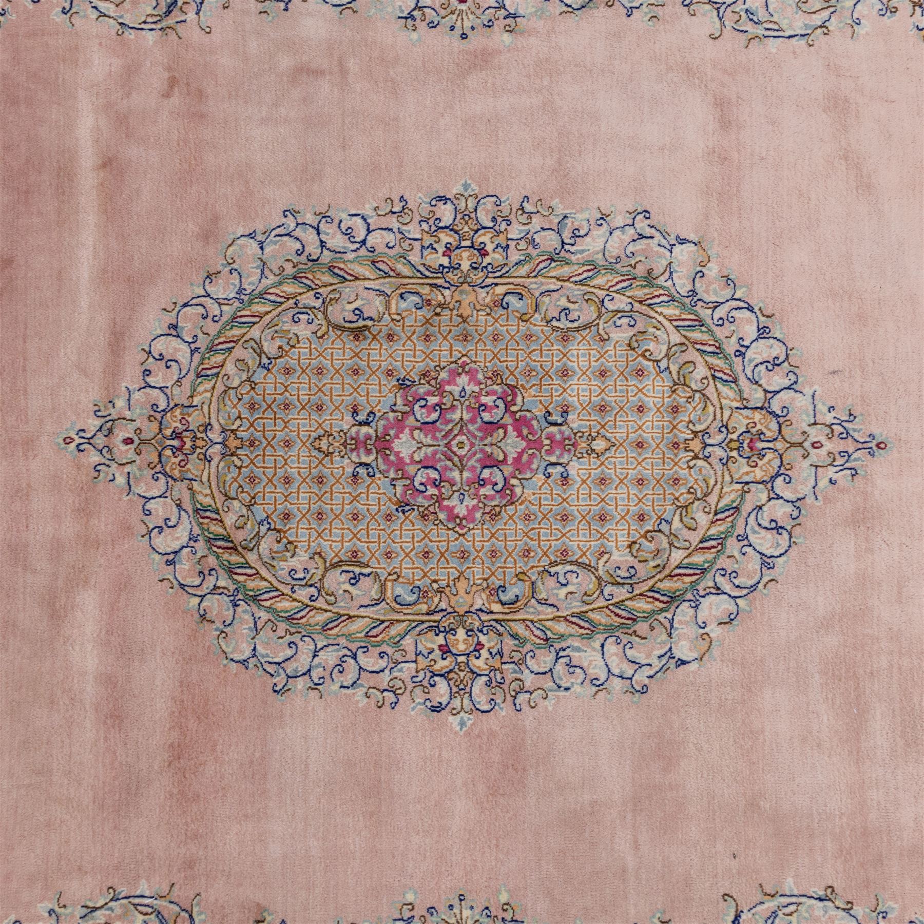 South East Persian Kirman hand-knotted rug, pale blush field with central scalloped medallion within an elaborate scalloped cartouche, spandrels filled with fine scrolling vine-work, palmettes and floral sprays, enclosed by wide and narrow borders in soft tones of blush pink, ivory, powder blue, sage green and pale gold, with cotton fringe ends 