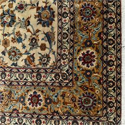 Kashan Persian rug, hand knotted, ivory ground rug, the rosette medallion decorated with projecting palmettes, on a field of swirling leafy branches and decorated with further palmettes, the scrolling border with repeating stylised plant motifs, within floral pattern guard stripes