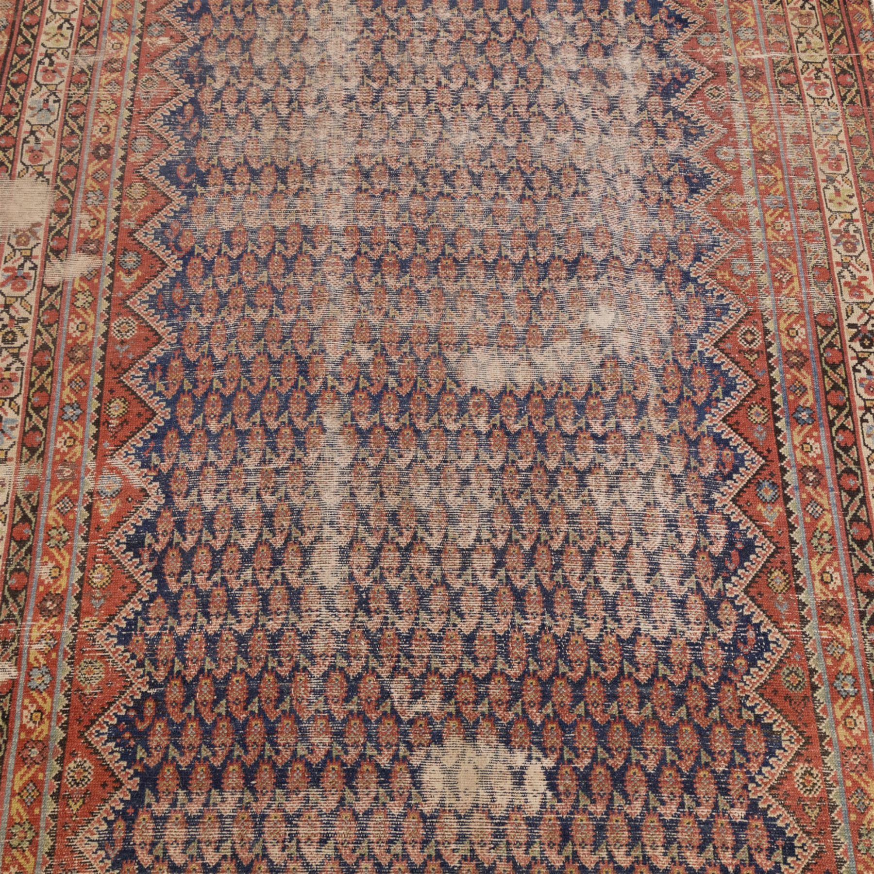 West Persian Kurdish vintage carpet, indigo field decorated with an all-over repeating boteh design arranged in diagonal rows framed by angular spandrels and enclosed by multiple geometric borders in a palette of indigo blue, madder red, soft green and ivory
