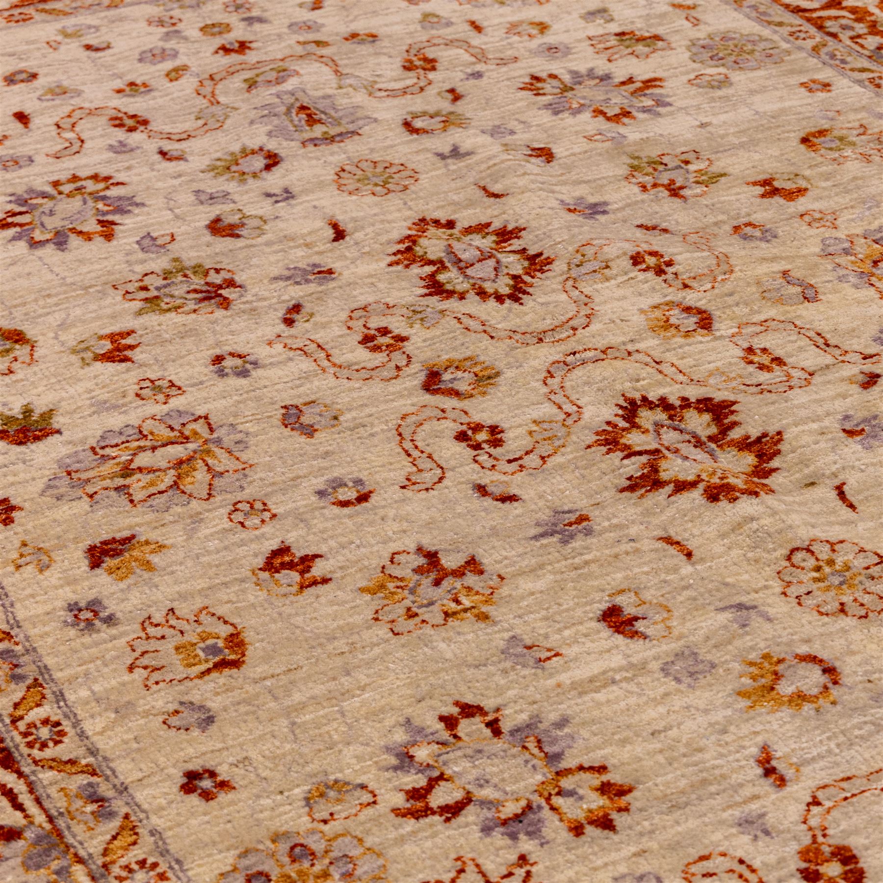 Indian Agra hand knotted rug, the pale beige field decorated with scattered floral sprays and stylised palmettes, enclosed within a wide terracotta border of scrolling foliage and flowerheads between narrow guard bands, finished with fringe ends