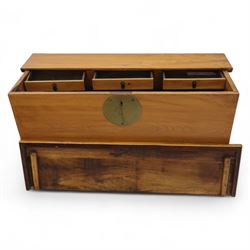 Burmese hardwood and brass inlaid marriage chest, the hinged top enclosing a fitted interior with small drawers, the front decorated with a circular brass medallion, raised on a plinth base