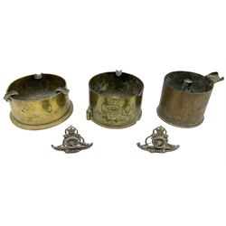 Trench Art - three WW2 brass shell case ashtrays, one mounted with Royal Artillery cap badge and button and one mounted with RA button; together with a pair of place name holders each formed from a Royal Artillery cap badge (5)