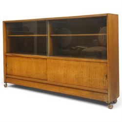 Herbert E Gibbs - Mid 20th century teak bookcase with sliding glazed doors, glazed upper section with adjustable shelf, above to two teak doors, raised on castors