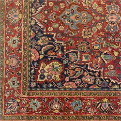 Persian Sarouk rug, richly decorated with an elaborate central medallion of palmettes and stylized floral motifs in indigo, ivory, and pastel tones on madder red ground, framed by spandrels, with a broad border of flowering palmettes and serrated leaves between a narrow floral guard border, fringe removed 
