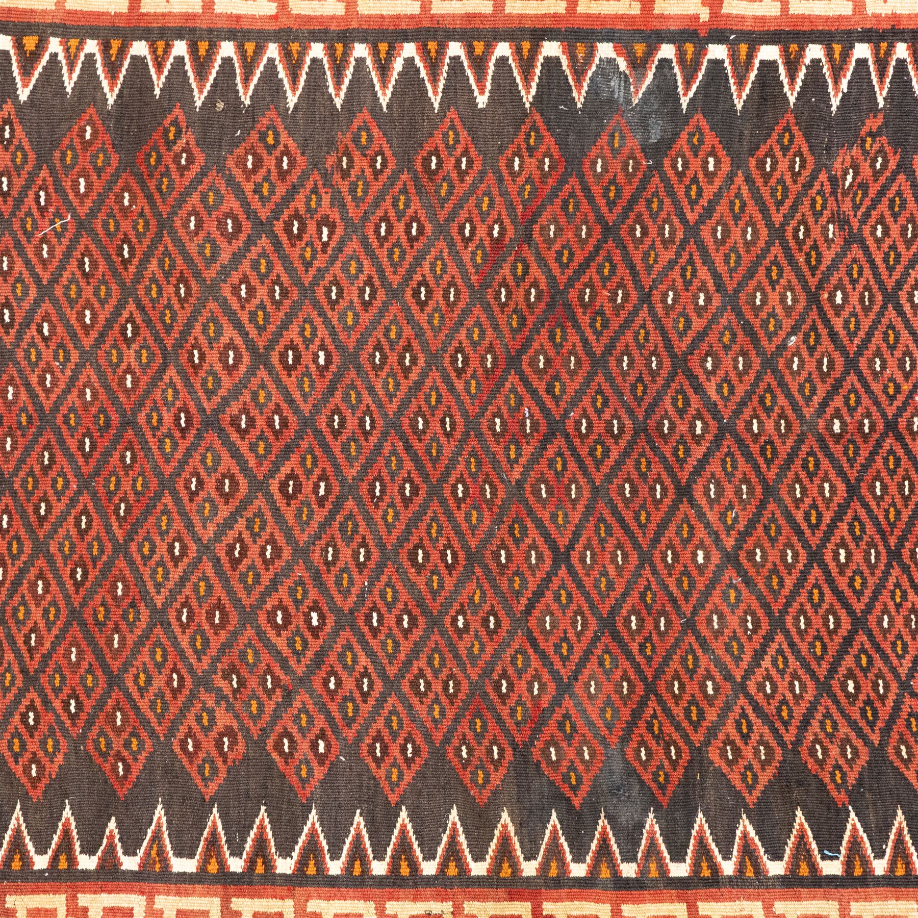 North west Persian Yamut Kilim, madder field with all-over lozenge lattice and serrated edges, with stepped end-panels and bold geometric borders in red, ivory and black