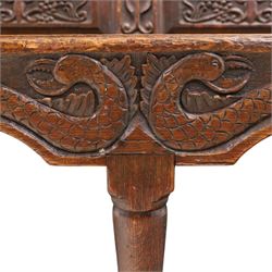 19th century Gothic Revival heavily carved oak settle or hall bench, the high quadruple back with moulded cresting rail over a frieze carved with stylised dolphin and sea creature motifs, the panels decorated with griffin and bird motifs with floral dividing rails, the shaped apron similarly carved with scaly sea beasts, on three cabriole front-supports united by stretchers