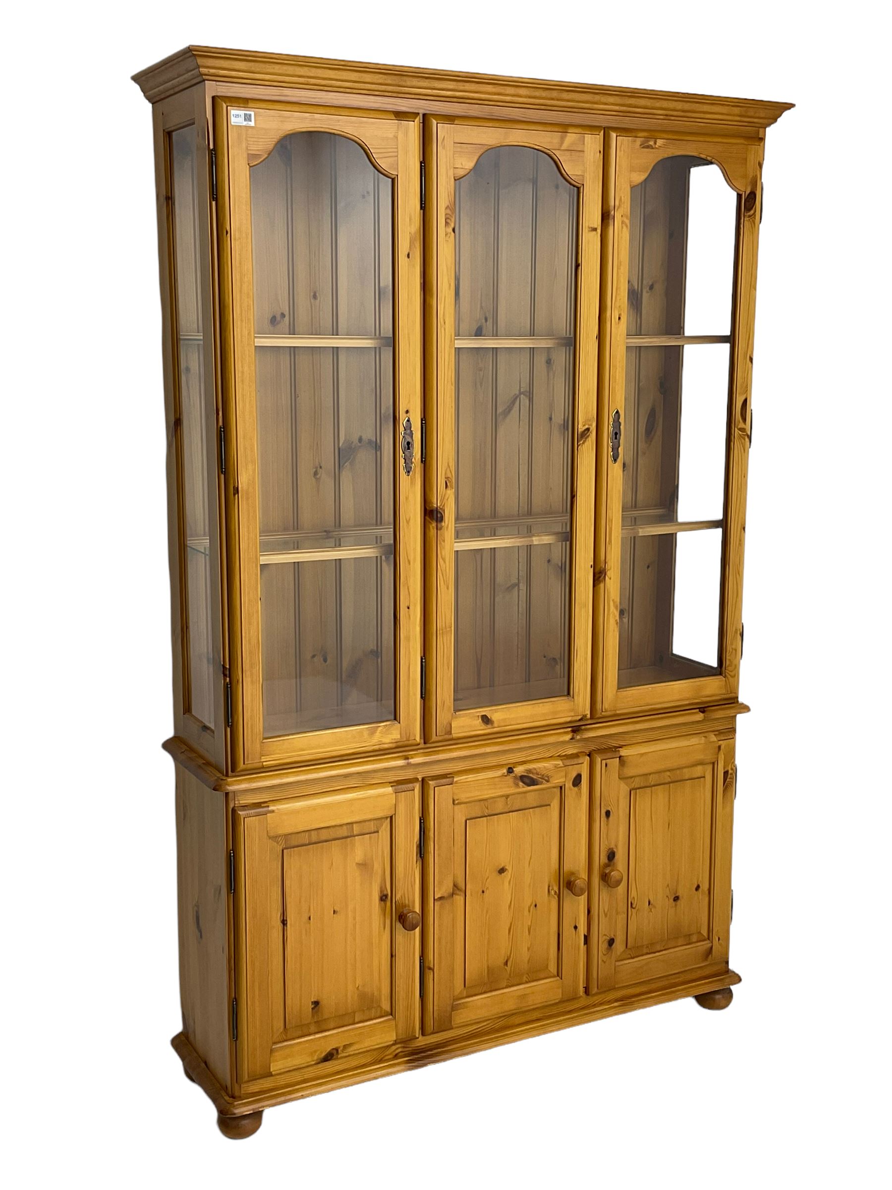 Pine display enclosed by glazed doors, fitted with three