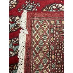 Persian Bokhara rug, red ground and decorated with three rows of Gul motifs, geometric pattern borders with stylised plant motifs