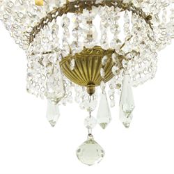 Empire design brass and crystal chandelier, the two circular brass tiers with foliate mounts, connecting the cascading crystal garlands, with prismatic drops