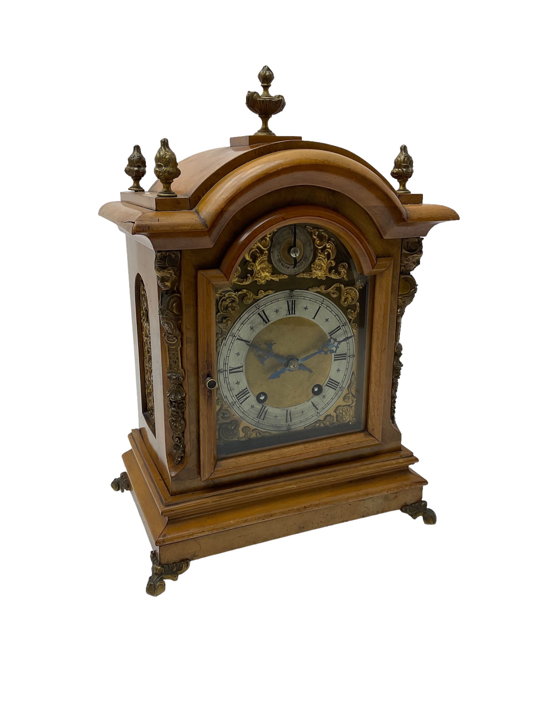 German - 19th century 8-day walnut bracket clock, striking the quarters on two coiled gongs, case with a break-arch top surmounted by cast brass finials, canted corners to the front with cast brass caryatids and sound frets to the sides, brass break arch dial with a silvered chapter ring, steel gothic hands, spandrels, and pendulum regulation dial. With pendulum.