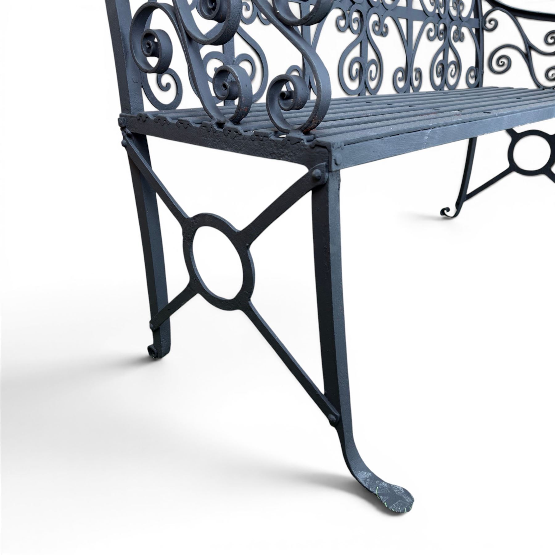 Regency period wrought iron garden bench, hand forged in wrought iron and finished in matt black paint, decorated with intricate scrollwork and featuring circular geometric ends, strapwork seat