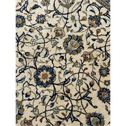 Persian Kashan ivory ground carpet, overall floral design, the field decorated with scrolling and interlaced leafy branches interspersed with palmettes, scrolling border decorated with stylised plant motifs, within floral pattern guard stripes 