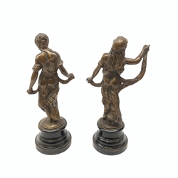 A pair of bronze figures, modelled as females in classical dress, each raised upon circular stepped base, largest H30cm. 