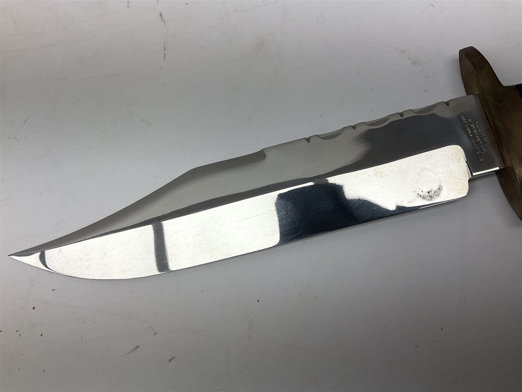 Large Bowie knife the 21cm steel blade marked J.E. Middleton & Sons Rockingham Street Sheffield with brass cross-piece and polished horn grip scales; in leather sheath L36cm overall