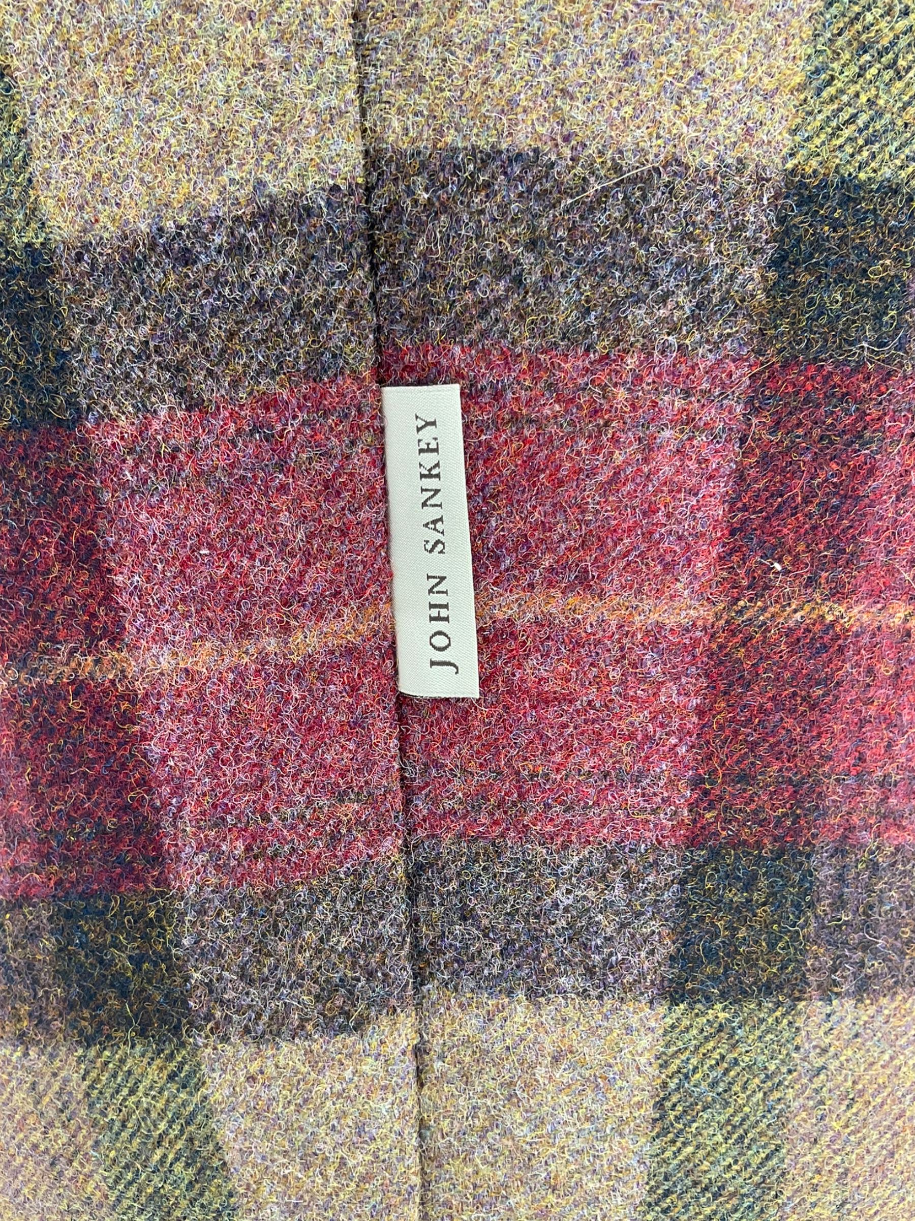 John Sankey - low armchair, buttoned back upholstered in tartan patterned fabric with contrasting grey leather, raised on turned and ebonised front feet with brass and ceramic castors, with matching foot stool