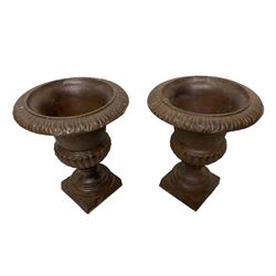 Two pairs of cast iron Campana-shaped garden urns, egg and dart moulded rim over gadrooned underbelly, on circular foot and square base 