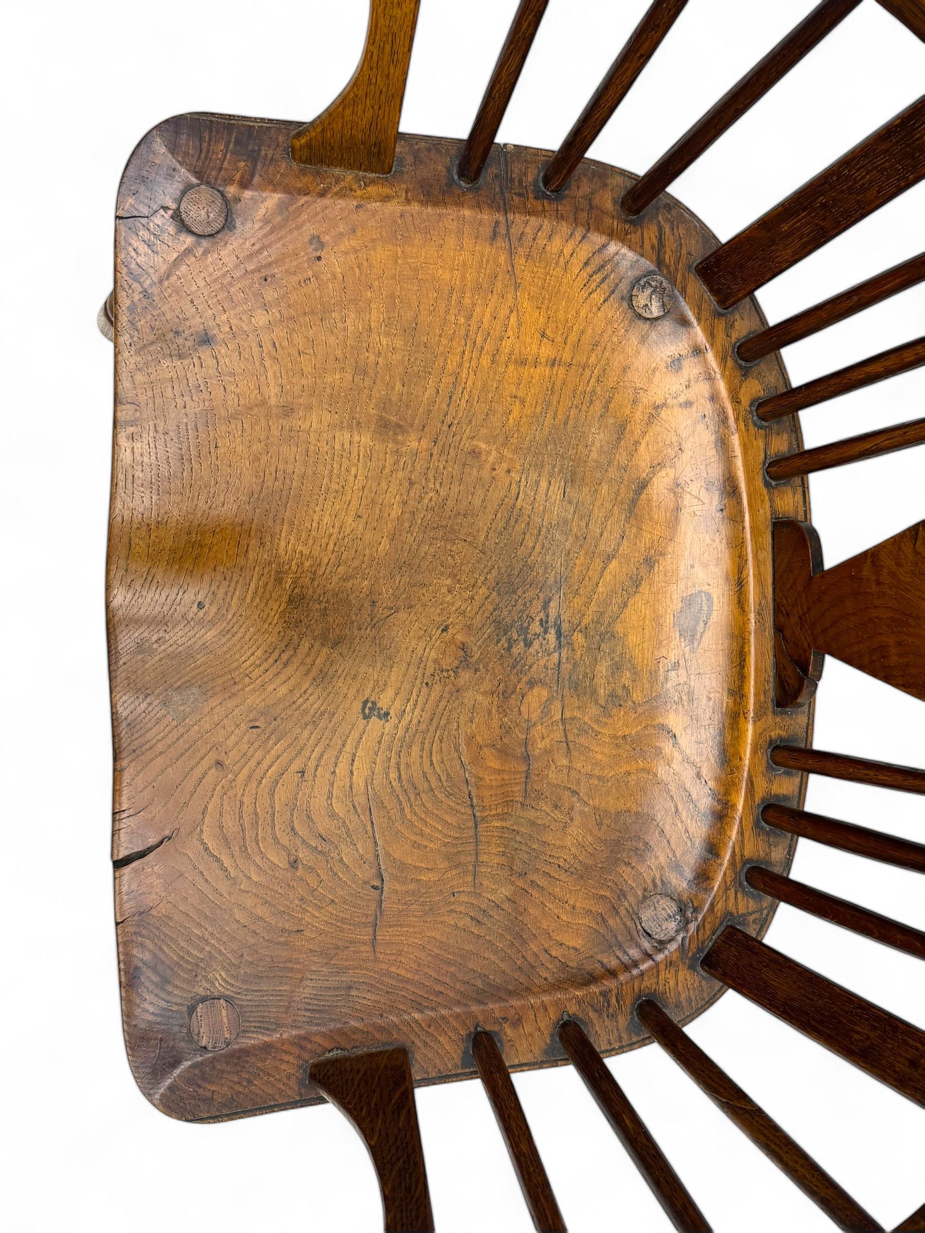 Early-to-mid 19th century elm and ash high-back Windsor armchair, central vase-shaped splat flanked by slender vertical spindles, outward-curving arms, shaped and dished saddle seat, raised on turned and splayed supports united by H-stretcher