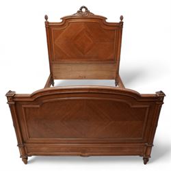 20th century French walnut 4' 6'' double bedstead, the headboard with flower head wreath pediment flanked by carved pineapple finials, reed and ribbon carved corner uprights, quarter-matched veneers, on turned feet, together with upholstered bed base
