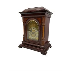 A Junghans two train mantle clock with a subsidiary third chiming train, in a mahogany and oak case with a concave raised top and deep cornice beneath,
With a glazed break arch door flanked by two turned and reeded oak pillars on a raised plinth with splayed feet, with an etched brass dial plate and silvered chapter ring with Arabic numerals, minute track and steel spade hands, eight-day movement striking the quarters on two gongs and the hours on five. With key and pendulum.




