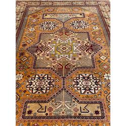 Shirvan Caucasian burnt amber ground carpet, central geometric pole medallion with four flanking octagonal lozenges surrounded by stylised flower heads, the border decorated with repeating geometric plant motifs and guarded by maroon bands